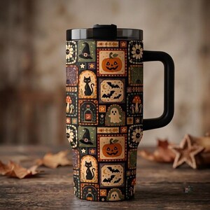 May include: A black-handled travel tumbler featuring a repeating pattern of rectangular tiles. Each tile displays Halloween-themed illustrations including orange pumpkins, black cats, witch hats, ghosts, bats, spiderwebs, and mushrooms.