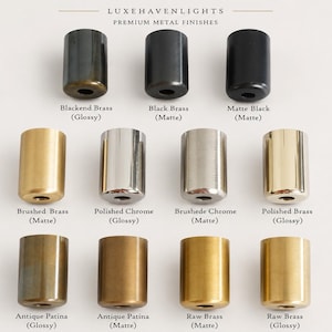 K&ouml;nnte beinhalten: Eine Sammlung von elf zylindrischen Metallkomponenten, angeordnet in drei Reihen, beschriftet mit LUXEHAVENLIGHTS PREMIUM METAL FINISHES. Die Oberfl&auml;chen umfassen geschw&auml;rztes Messing, schwarzes Messing, Mattschwarz, geb&uuml;rstetes Messing, poliertes Chrom, geb&uuml;rstetes Chrom, poliertes Messing sowie Antik-Patina und rohes Messing in gl&auml;nzenden und matten Texturen.