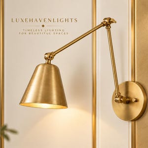 May include: A brass wall-mounted swing arm lamp with a conical shade and adjustable joints. The text LUXEHAVENLIGHTS and TIMELESS LIGHTING FOR BEAUTIFUL SPACES is visible above the lamp. The fixture features a circular base and metallic finish.