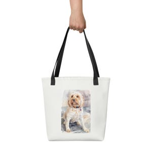 Könnte beinhalten: Eine weiße Tragetasche mit schwarzen Henkeln, mit einem Aquarellgemälde eines hellbraunen Hundes mit schwarzem Halsband und herzförmigem Anhänger. Der Hund sitzt auf einer blau-grauen Oberfläche.