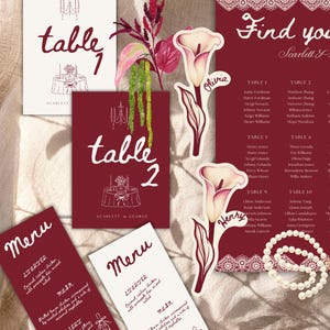 May include: A wedding stationery set featuring deep red and white table numbers, menus, and a seating chart with lace borders. Includes calla lily place cards with names, a string of white pearls, and a decorative floral sprig with green and red leaves.