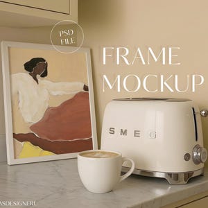 May include: A white framed art print featuring an abstract figure in a white shirt and red skirt, a cream-colored Smeg toaster, and a white ceramic mug filled with coffee. The text "PSD FILE" and "FRAME MOCKUP" are visible in the image.