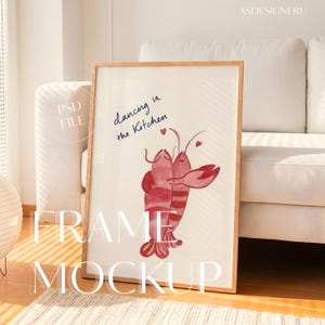 Op de afbeelding: Een verticale houten lijst met een aquarelillustratie van twee rode kreeften die elkaar omhelzen met kleine rode hartjes erboven. De tekst "dancing in the Kitchen" staat in blauw schrift boven de kreeften. De lijst wordt getoond als een mockup.