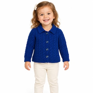 May include: A vibrant royal blue cable knit cardigan featuring a classic collar, long sleeves, and a front button closure with four matching blue buttons. The garment is crafted with a textured cable pattern and ribbed cuffs and hem.