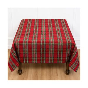 May include: A square tablecloth featuring a vibrant red tartan plaid pattern with intersecting thin lines in dark green, black, and yellow. The fabric drapes over the four sides of a table, displaying a consistent woven texture throughout the design.