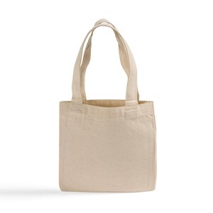May include: A plain, off-white canvas tote bag with two matching fabric handles. The bag features a rectangular body with a flat base and visible stitching along the top edge and handle attachments, presenting a simple, unadorned construction.