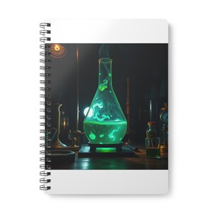 May include: A spiral-bound notebook featuring a graphic of a glowing green liquid inside a glass laboratory flask. The flask sits on a dark base, emitting wisps of vapor, surrounded by various scientific instruments in a dimly lit setting.