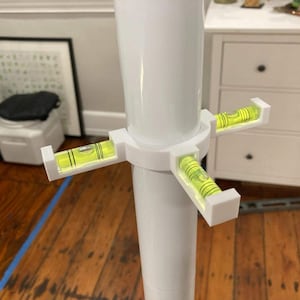 May include: White plastic leveler with four built-in bubble levels. The levels are attached to a white pole.