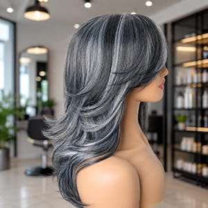 May include: A shoulder-length wig featuring layered, feathered hair in a blend of charcoal gray, silver, and white highlights. The hair is styled with side-swept bangs that frame the face, showcasing a multi-tonal color palette and a textured, voluminous appearance with soft, flowing waves throughout the length.