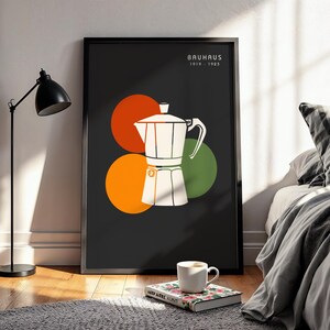 May include: A framed wall art print featuring a white moka pot illustration centered over overlapping orange, red, and green circles on a dark gray background. The text "BAUHAUS 1919-1933" is printed in white in the upper right corner of the print.