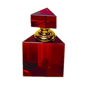 May include: A red, geometric perfume bottle with a gold-colored base and a pyramidal stopper. The bottle has a square base and a faceted design, reflecting light. The overall design is modern and luxurious.