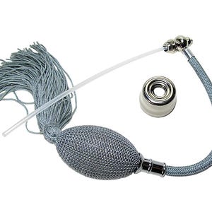 May include: A silver-gray perfume atomizer bulb with a matching fabric-covered hose and a long, thin, clear plastic tube. The set includes a separate silver-toned metal collar piece with a white base, designed for attachment to a glass bottle.