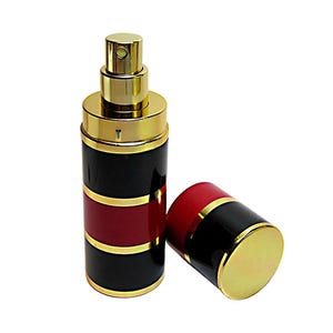 May include: A cylindrical perfume atomiser featuring a black and red striped body with gold-tone metal accents. The bottle has a gold spray nozzle at the top and a matching removable cap with a gold top, black middle, and red bottom section.