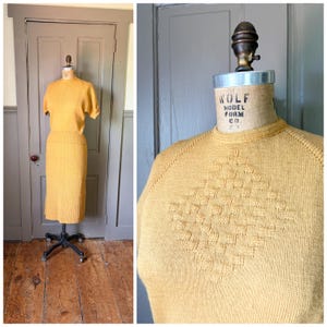 Peut inclure: Un ensemble en tricot jaune moutarde composé d'un haut à manches courtes et d'une jupe côtelée. Le haut présente un motif en losange texturé sur la poitrine. Le vêtement est présenté sur un mannequin Wolf Model Form Co. à col rond.