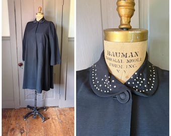 Un abrigo negro de manga larga estilo swing de los años 50, modelo "A Starry Evening", con tachuelas metálicas plateadas y detalle de pedrería en el cuello. Talla mediana.