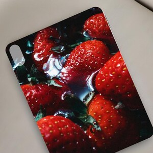 May include: A phone case featuring a close-up image of ripe red strawberries with green leaves, partially submerged in water. The text "MOODY STRAWBERRY" is printed at the top.