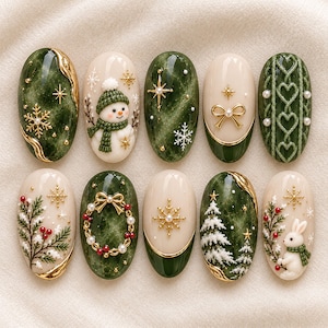 May include: A set of ten oval-shaped press-on nails featuring festive holiday designs. The nails display deep green and cream backgrounds with gold accents, including raised 3D motifs of a snowman, a rabbit, snowflakes, pine trees, and wreaths.