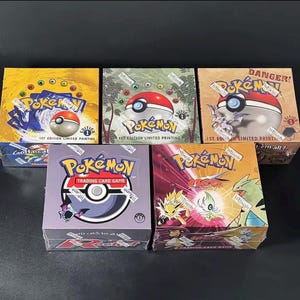 May include: Five sealed Pokémon trading card game booster boxes including Base Set, Jungle, Fossil, Team Rocket, and Neo Destiny editions. Each box features the Pokémon logo, a Poké Ball graphic, and 1st Edition branding on the packaging.