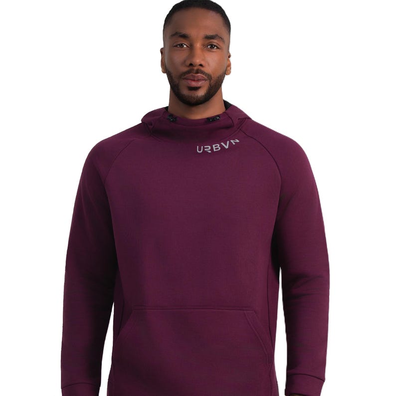 May include: A burgundy hoodie with a kangaroo pocket and a high collar. The word "URBVN" is printed in light gray on the collar. The hoodie has a drawstring hood and long sleeves. The model is wearing the hoodie.