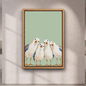 Pode incluir: Uma impressão de arte emoldurada apresentando quatro gaivotas brancas e cinzentas com bicos e patas cor de laranja, alinhadas sobre um fundo verde sálvia claro. A obra está contida numa moldura de madeira clara com um rebordo definido.