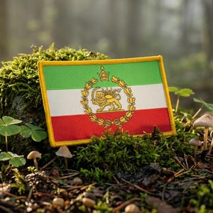 May include: A rectangular embroidered patch featuring the horizontal green, white, and red tricolour flag of Iran. Centred on the white stripe is a gold emblem depicting a lion holding a sword, surrounded by a circular wreath and a crown.
