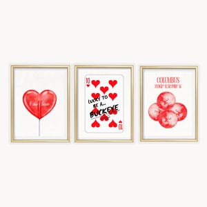 May include: Three framed wall art prints with gold borders. The first shows a red heart-shaped lollipop with the text Ohio State. The second is a ten of hearts playing card with the text Lucky To Be A... Buckeye. The third shows red disco balls.