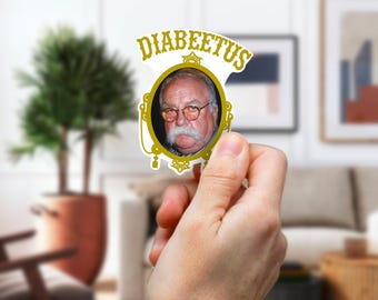 May include: A white sticker with a gold frame and the word "Diabeetus" in gold letters. Inside the frame is a photo of a man with a mustache and glasses.