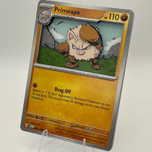 Puede incluir: Una carta de Pokémon Primeape con una ilustración de dibujos animados de una criatura parecida a un mono marrón y beige con guantes de boxeo. La tarjeta tiene un borde amarillo y plateado con el texto "Primeape" y "Drag Off".