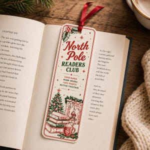 May include: A rectangular paper bookmark with a red ribbon at the top, featuring the text North Pole READERS CLUB, GOOD BOOKS, WARM DRINKS, COZY NIGHTS, BETTER TOGETHER, and illustrations of a Christmas tree, a fireplace, and books.