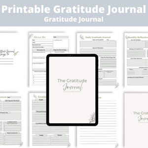 以下が含まれることがあります： 画面に「The Gratitude Journal」と表示されたデジタルタブレット。その周囲には、「About Me」、「Daily Gratitude Journal」、「Monthly Reflections」、「My 5-Minute Gratitude」などのセクションが記載された、罫線付きの印刷可能なジャーナルページが複数配置されています。