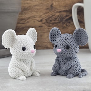 May include: Two small mouse figurines, one white and one gray, featuring a textured, knit-like surface pattern. Each mouse has large rounded ears, small black bead eyes, and a tiny pink nose. The figures are seated in an upright position.