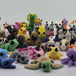 May include: A large collection of small, articulated animal figurines in various colors and species. The group includes creatures like turtles, frogs, dolphins, foxes, and mythical animals, all featuring large black eyes and segmented bodies.