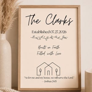May include: A rectangular framed wall art print on a light beige background featuring the text The Clarks, Established 07.27.2026, Built on Faith, Filled with Love, a line drawing of two houses, and the quote As for me and my house, we will serve the Lord. —Joshua 24:15.