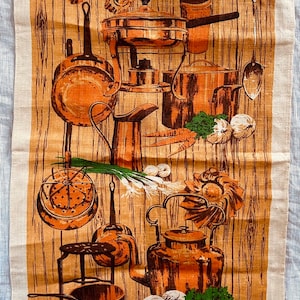 May include: A vintage kitchen tea towel with a brown and white woodgrain background. The towel features a collection of copper kitchenware, including pots, pans, a kettle, and a strainer. There are also vegetables and herbs, such as carrots, onions, and parsley, depicted on the towel. The towel is made of all linen and has a label that reads "All Linen".