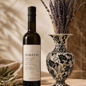 Peut inclure: Une bouteille en verre foncé d'huile d'olive extra vierge Karataş avec une étiquette blanche portant le texte Karataş, Naturel Sızma, Extra Virgin, Erken Hasat, Early Harvest, Soğuk Sıkım, Cold Extracted, Yerkesik Muğla, à côté d'un vase floral noir et blanc.