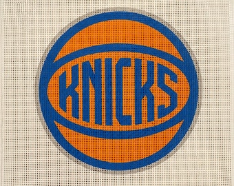 Może przedstawiać: Okrągłe płótno do haftu z motywem piłki do koszykówki w żywych kolorach pomarańczowym i niebieskim. Słowo KNICKS jest wyśrodkowane pogrubionymi niebieskimi literami na pomarańczowej grafice piłki, na kwadratowym tle z siatki w kolorze złamanej bieli.