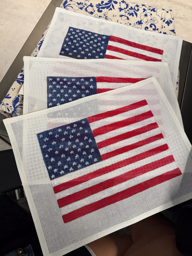 May include: Three rectangular needlepoint canvases featuring a printed American flag design. Each canvas displays a blue field with white stars and horizontal red and white stripes on a white mesh grid background, ready for embroidery stitching.