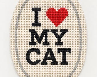 Może przedstawiać: Owalne płótno do haftu z wyszytym czarnym napisem I, MY oraz CAT, gdzie czerwony wyszyty symbol serca zastępuje słowo love. Wzór jest otoczony cienką, szarą, wyszytą owalną ramką na siatkowej tkaninie w kolorze kremowym.