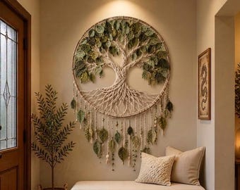 Puede incluir: Un gran tapiz circular para pared con un diseño de árbol de la vida en macramé, con raíces y ramas anudadas. El árbol está adornado con numerosas hojas de tela verde y hebras colgantes con pequeñas cuentas, creando un efecto texturizado.