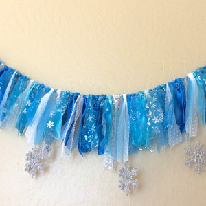 May include: A blue and white fabric banner with snowflake designs, ideal for a winter or Frozen-themed party.