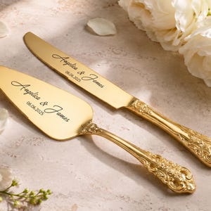 Può includere: Un set composto da coltello e paletta per torta color oro con manici decorati e in rilievo. Entrambi gli articoli sono incisi con i nomi Angelica & James e la data 06.06.2025 in un carattere corsivo nero. Le superfici metalliche sono lucide.