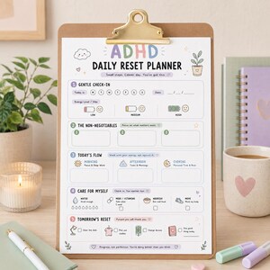 May include: A brown clipboard holding a white ADHD Daily Reset Planner sheet with pastel-colored headers and icons. The planner includes sections for a gentle check-in, non-negotiables, today's flow, self-care, and tomorrow's reset with various prompts.