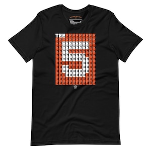 Puede incluir: Una camiseta negra de manga corta con un diseño gráfico en el pecho. El diseño consiste en una cuadrícula de letras E naranjas con la palabra TEE en la parte superior izquierda, y una gran E blanca formada por el espacio negativo en la cuadrícula.
