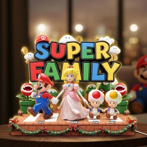 May include: A decorative Super Mario themed display featuring figures of Mario, Princess Peach, and two Toads standing on a brick-patterned base. The text SUPER FAMILY is displayed above the figures, with labels DADDY, MOMMY, BRIAN, and NANCY below.
