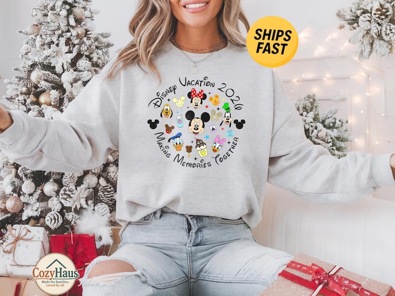 May include: A light gray crewneck sweatshirt featuring a circular graphic with various Disney character faces, including Mickey Mouse, Minnie Mouse, Donald Duck, and Goofy, with the text Disney Vacation 2020 Making Memories Together.