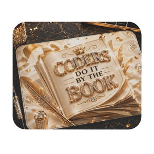 May include: A decorative mousepad featuring a book design with the text "CODERS DO IT BY THE BOOK". The book and text are embellished with sparkling gold and diamond-like accents. A gold feather and pen are also visible.