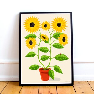 May include: Framed art print depicting a stylized illustration of sunflowers in a terracotta pot. The sunflowers have yellow petals and dark brown centres, with green leaves and stems. A small ladybird rests on one of the leaves.