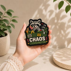 May include: A rubber patch featuring a cartoon raccoon inside a green dumpster filled with trash, including a donut, pizza, and a fish skeleton. The text reads TRASH PANDA, DO NOT FEED, and CHAOS COORDINATOR in bold white and yellow lettering.