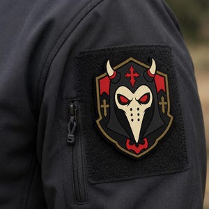May include: A black tactical jacket sleeve featuring a rectangular hook-and-loop patch area with a shield-shaped morale patch. The patch displays a cream-colored plague doctor mask with red eyes, horns, and a red cross on a black background.