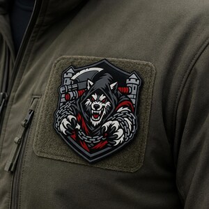 May include: A tactical olive green jacket featuring a rectangular hook-and-loop patch. The patch displays a graphic of a snarling wolf wearing a dark hood, holding a large axe, and wrapped in silver chains against a grey castle tower background.
